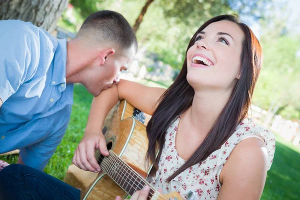 在公园里和男朋友玩吉他的年轻成年女孩 — 图库照片