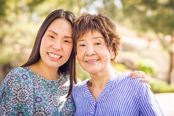 Outdoor portrait of a happy Chinese mother and daughter.