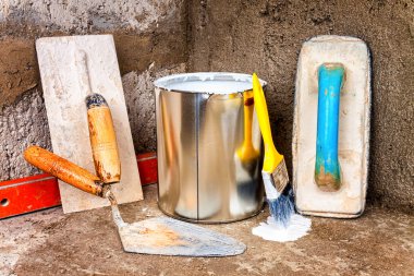 Paint can and masonry tools on a rough concrete surface