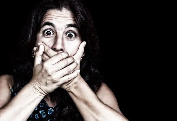 Donna spaventata che copre la bocca isolata su nero — Foto Stock