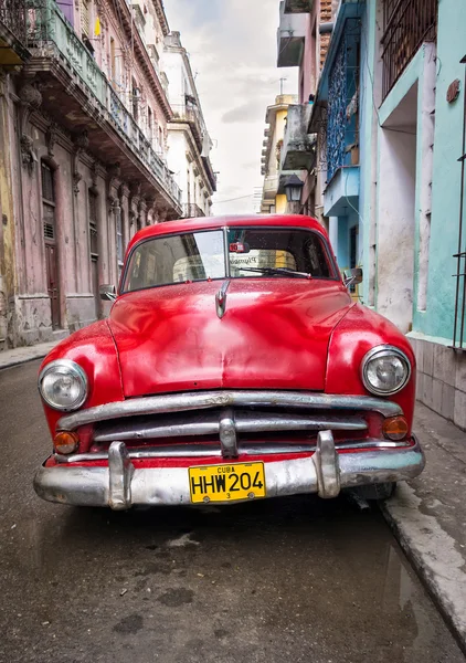 Oude rode auto in een sjofel straat in havana Stockfoto