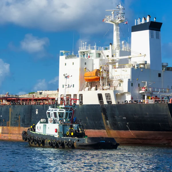 Sleepboot begeleiden een enorme vrachtschip — Stockfoto