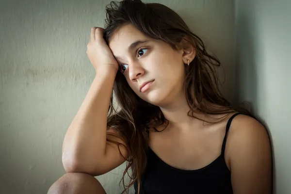 Triste menina hispânica sentado em um canto — Fotografia de Stock