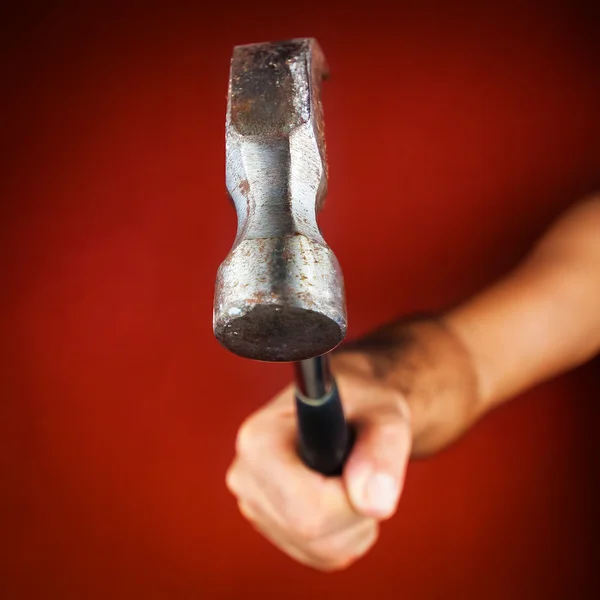 Hand hält einen Hammer auf leuchtend rotem Hintergrund — Stockfoto