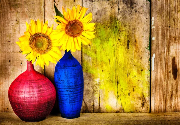 Barevné vázy s slunečnice na dřevo pozadí — Stock fotografie