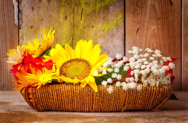 Цветы на корзине на деревенском деревянном фоне — стоковое фото