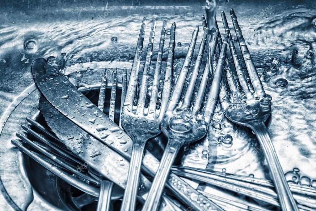 Forks and knives washed on a kitchen sink