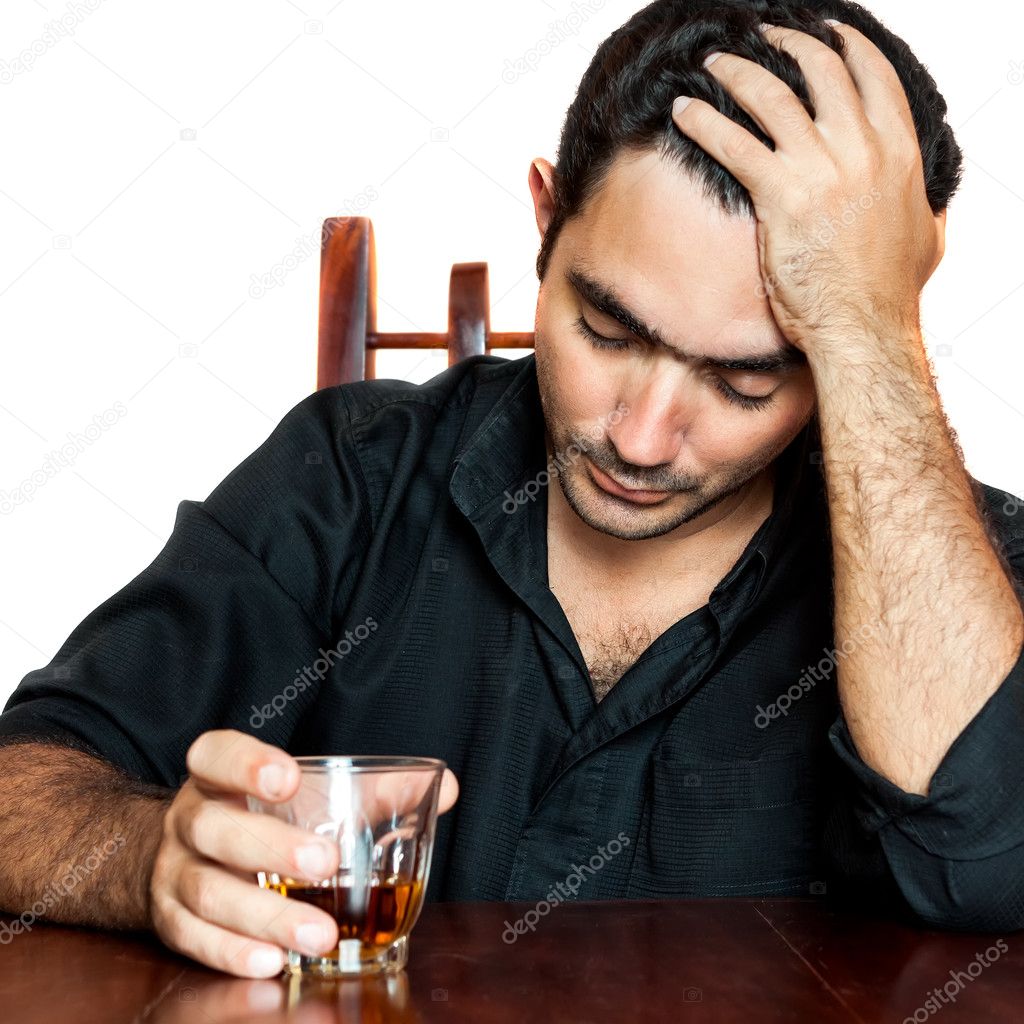 Hispanic man holding an alcoholic drink and suffering a headache