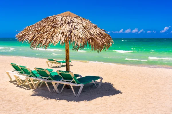 Sombrillas de paja y camas de playa en una playa cubana — Foto de Stock