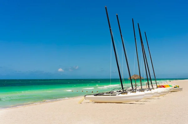Zeilboten en waterfietsen op een strand in cuba — Stockfoto