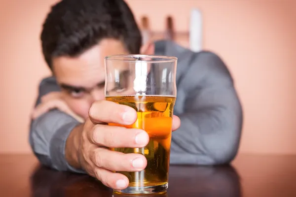 Hombre hispano borracho sosteniendo un vaso de cerveza — Stockfoto