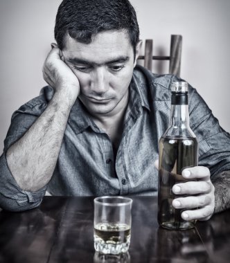 liquo bir şişe ve bardak ile katta oturan drunkman