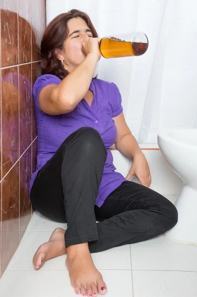 Latijns-vrouw dronken liggend in de badkamer en drinken — Stockfoto