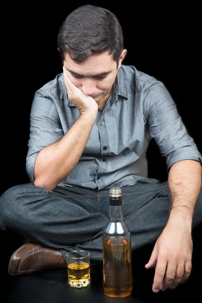 Drunkman zittend op de vloer met een glas en een fles liquo — Stockfoto