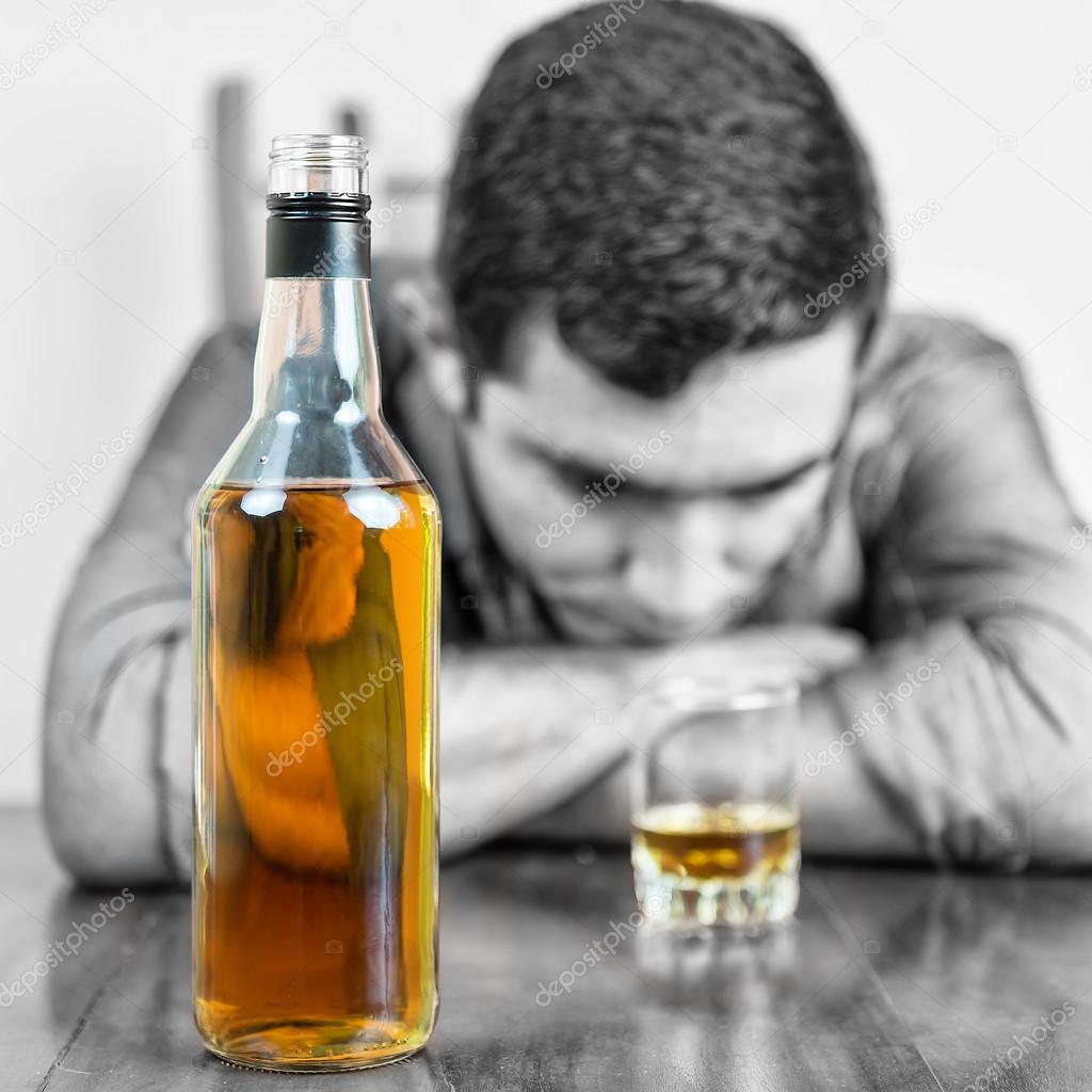 Whisky bottle with an out of focus drunk man
