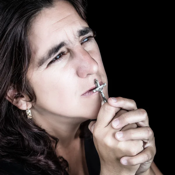 Hispanische Frau betet und küsst ein Kruzifix — Stockfoto