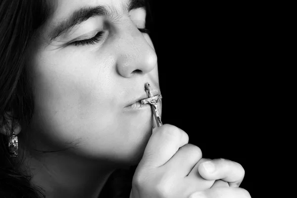 Mulher hispânica beijando um pequeno crucifixo — Fotografia de Stock