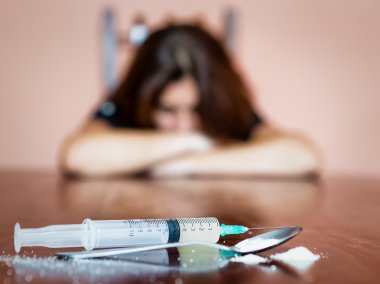 Syringe and drugs with out of focus female addict clipart