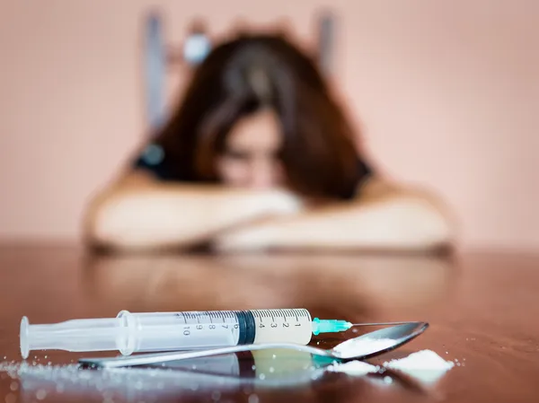 Jeringa y drogas con adicto femenino fuera de foco — Foto de Stock