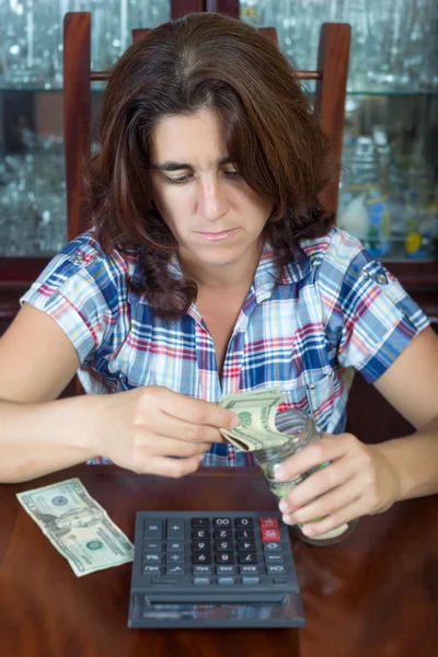 Worried hispanic woman counting her savings at home — Stock Photo, Image