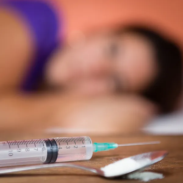 Drogas e seringa com viciado em sexo feminino fora de foco — Fotografia de Stock