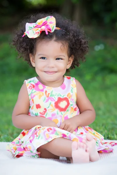 Kleines Mädchen mit Afro-Frisur sitzt auf dem Gras — Stockfoto