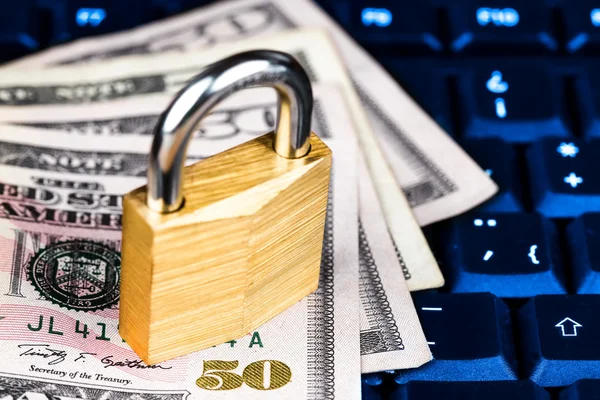Closed padlock over a stack of money on a keyboard — Stock Photo, Image