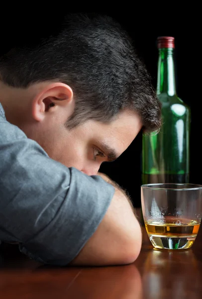 Deprimerad berusad man stirrar på ett glas whisky — Stockfoto