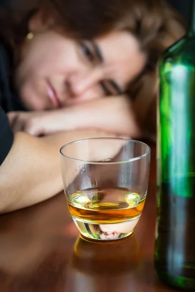 Dronken vrouw staren naar een glas whiskey — Stockfoto