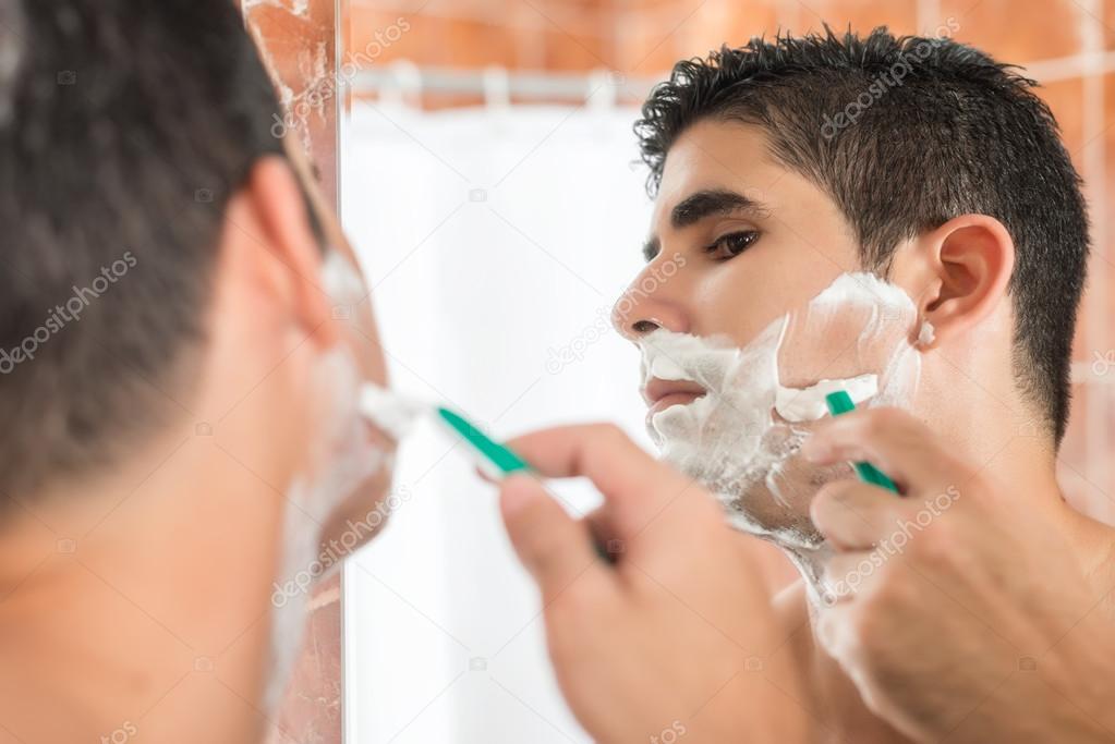 Young hispanic man shaving
