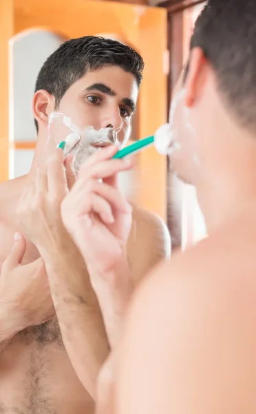 Hombre hispano sin camisa afeitándose delante de un espejo — Foto de Stock