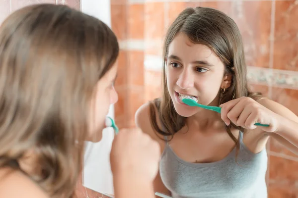 Girl brushing her teeth in front of a mirror — Stock Photo, Image