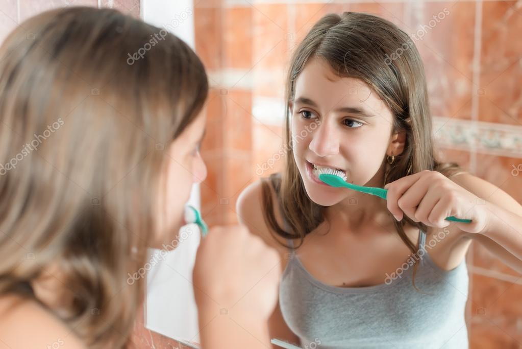 Girl brushing her teeth in front of a mirror — Stock Photo © kmiragaya