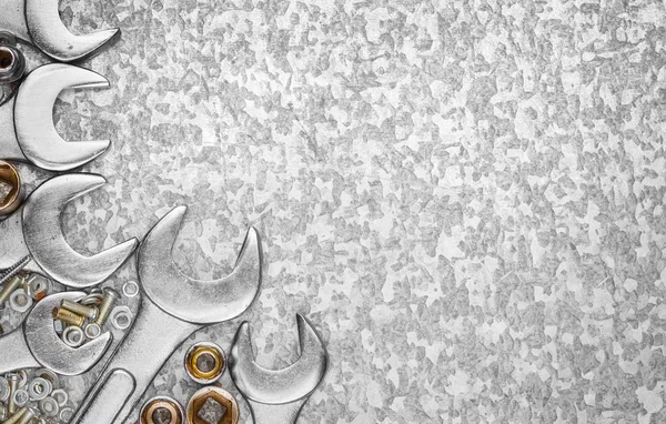 Wrench tools and nuts on a metallic background — Stock Photo, Image