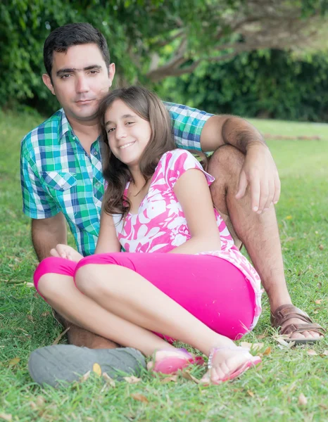 Adolescente et son père assis dans l'herbe à un beau par — Photo