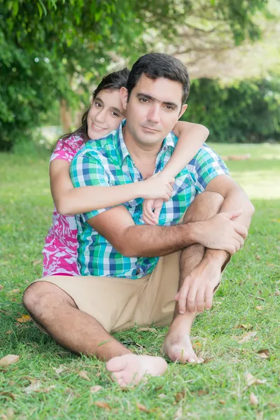 Hispanic teenage girl hugging her  father at a park outdoors — Stock Photo, Image