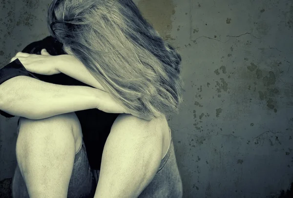 Молода жінка плаче, сидячи на підлозі — стокове фото