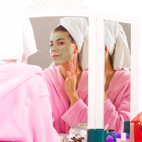 Beautiful young woman in towel doing cosmetic mask on her face — Stock Photo, Image