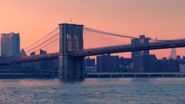 East River üzerindeki Brooklyn Köprüsü New York 'tan gün batımında Aşağı Manhattan' ın rıhtımından izlendi