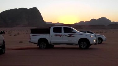 Ürdün Haşim Krallığı 'ndaki Wadi Rum çölünde Ay Vadisi olarak da bilinen arabalar ve turistler.