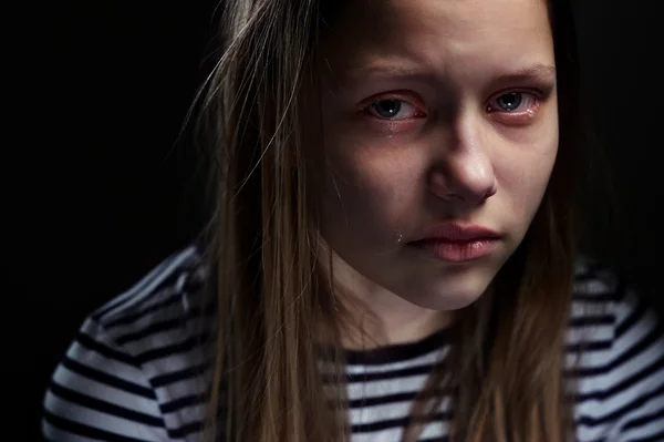 Dark portrait of a crying teen girl, studio shot