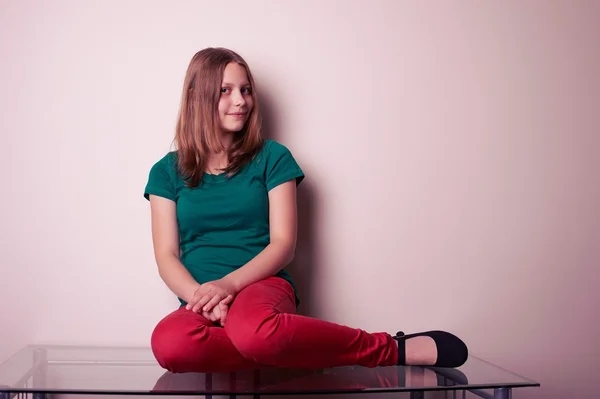 Портрет девочки-подростка, сидящей на столе — стоковое фото