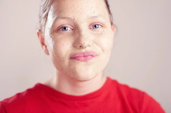 Felice ragazza adolescente con maschera scrub sul suo viso — Foto Stock