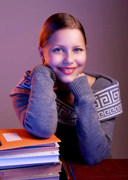 Kitaplar ile masada oturan bir genç kız — Stok fotoğraf