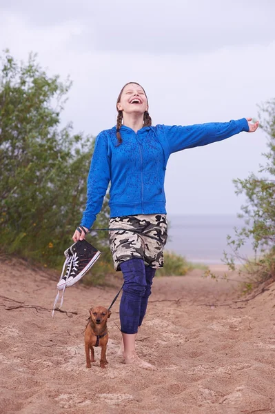 Tiener meisje permanent op het strand met haar hond — Stockfoto