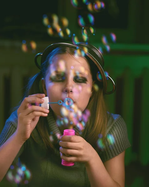 Triest tiener meisje zit en blaast zeepbellen — Stockfoto