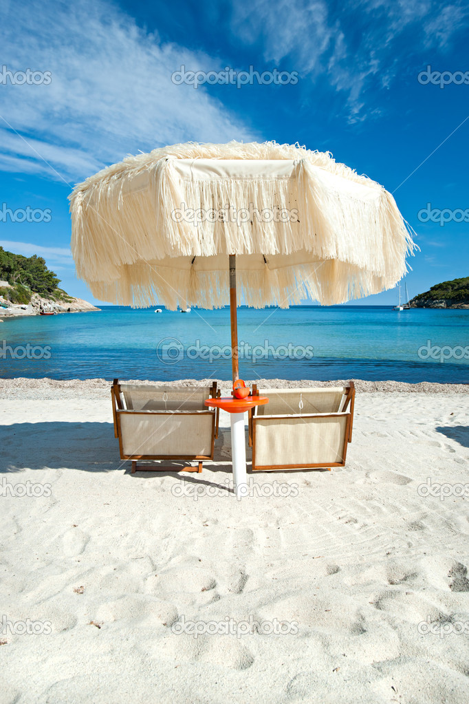 Two beach chairs with umbrella.
