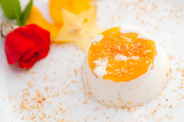 Italiensk dessert pannacotta på vit platta dekorerad med kokosmjölk och persika. — Stockfoto