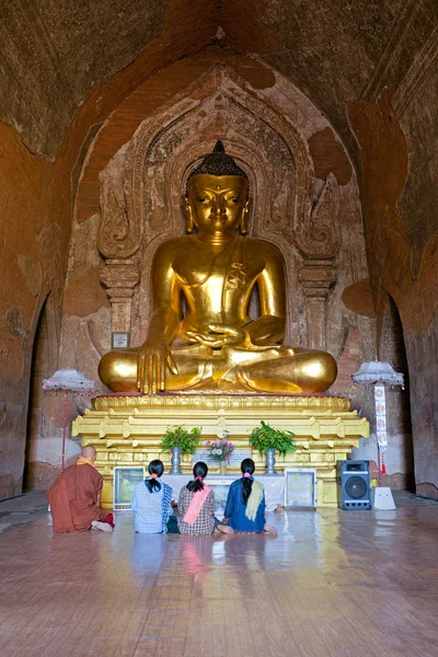 Mnich i trzy kobiety modląc się wewnątrz świątyni htilominlo, Pagan-Birma, — Zdjęcie stockowe