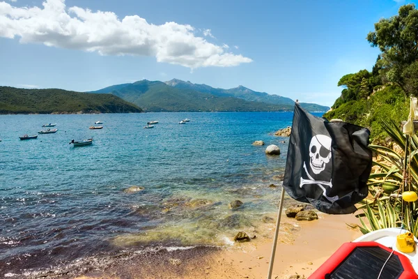 Pirate vlag in forno strand, biodola bay, elba eiland. — Stockfoto